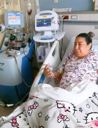 Jessica Ceja sits in a hospital bed in hello kitty pajamas hooked up to an infusion machine